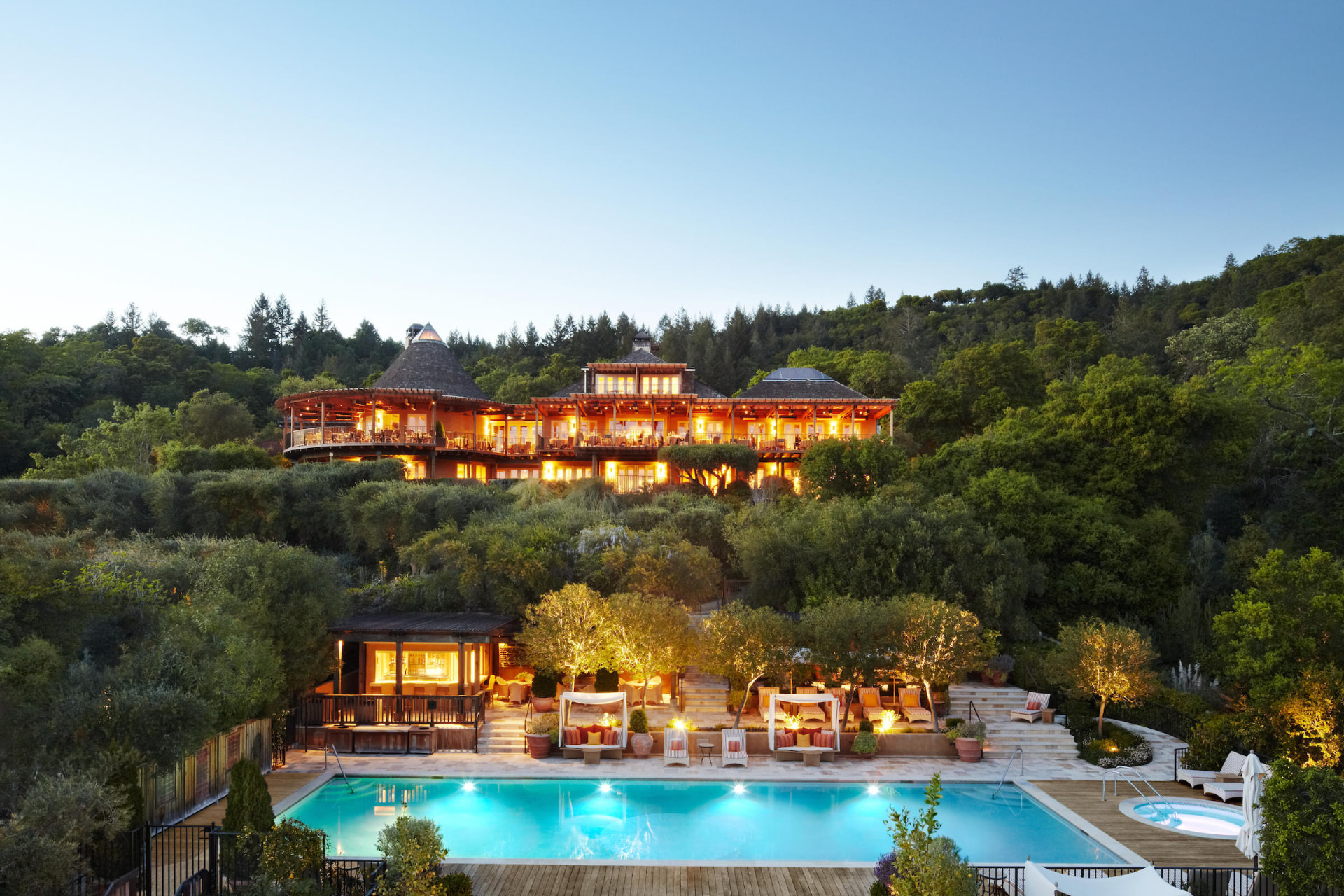 Auberge du Soleil at dusk — the hillside hotel glowing above its pool and olive grove, Rutherford